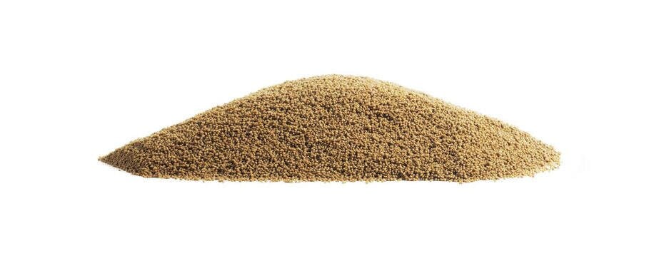 Her ser vi hvordan fôrpellets ser ut. En øse pellets ligger på et bord for at vi skal kunne se et nærbilde av fôret.  Her ser vi hvordan fôrpellets ser ut. En øse pellets ligger på et bord for at vi skal kunne se et nærbilde av fôret.